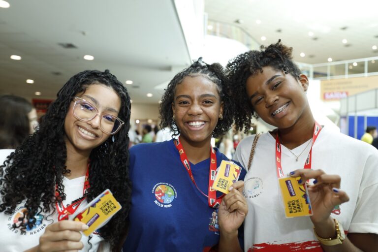 Três estudantes baianas sorrindo em ambiente escolar, representando os investimentos do Governo da Bahia em educação, leitura e cultura na campanha Do Lado da Cultura 2026.
